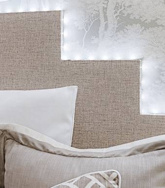 promenor da cabeceira de cama feita com placas de madeira e papel de parede e com contorno feito com fitas led
